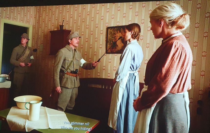 Johanna Lecklinin elokuvasta otetussa kuvakaappauksessa kaksi valkoista sotilasta uhkailee äitiä ja tytärtä näiden kodissa.